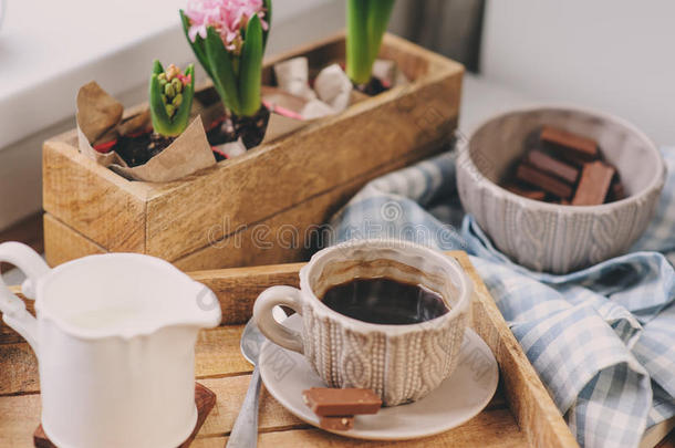 舒适的冬天早晨在家。 木制托盘上的咖啡、牛奶和巧克力。 <strong>背景</strong>上的风信子花。 温<strong>暖</strong>的<strong>心</strong>情
