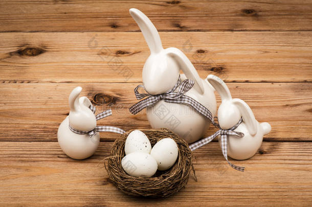 复活节装饰-兔子与复活节鸡蛋在巢在木制背景。