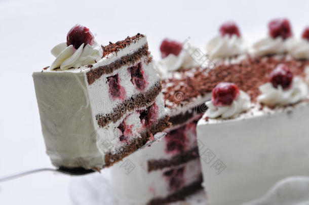 奶油蛋糕与巧克力屑和樱桃在金属勺子，生日蛋糕在白色盘子，糕点，摄影为商店