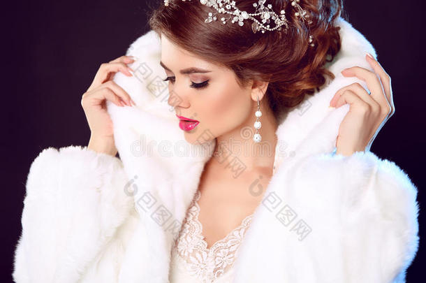 美丽时尚模特女孩穿着白色貂皮大衣。 婚礼发型。 化妆。 美丽奢华的冬天女人被隔离在黑暗中