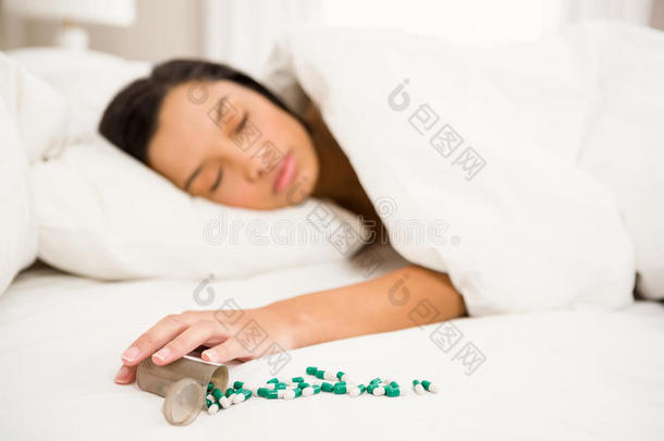 黑发女人在床上睡觉，洒了一瓶药丸