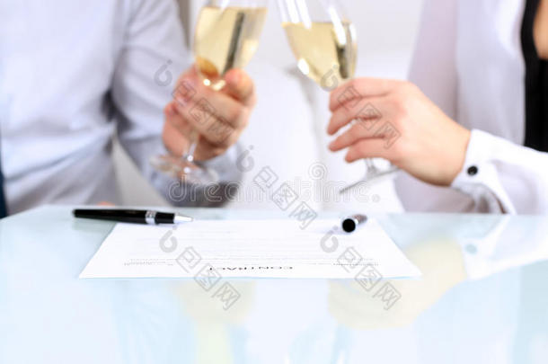 合同的特写图像。 两位同事庆祝与香槟签订合同