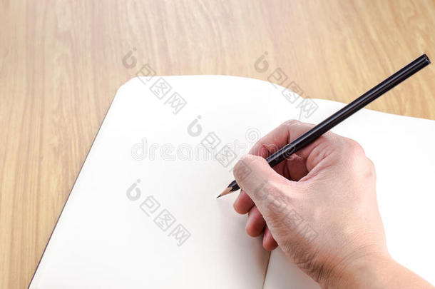 手拿黑色铅笔写在空白打开的笔记本上的宇