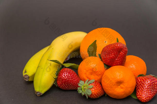 香蕉，<strong>苹果</strong>，<strong>橘子</strong>，草莓和三个<strong>橘子</strong>，叶子在一个美丽的灰色背景，美丽的颜色和装饰