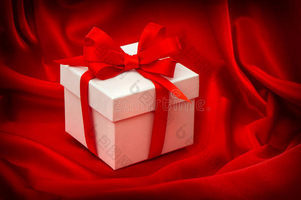 红色丝绸上有蝴蝶结丝带的礼品盒
