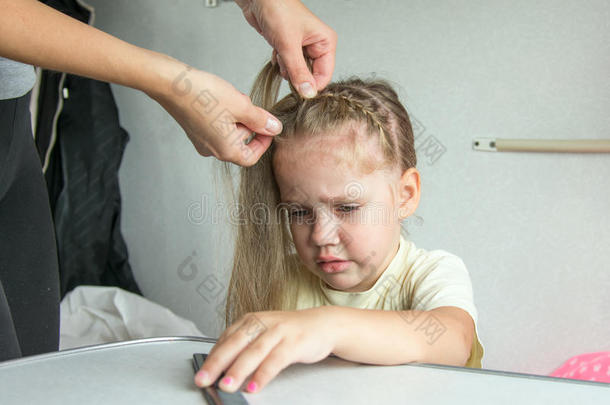 四岁的女孩在妈妈梳头时<strong>痛苦地</strong>哭