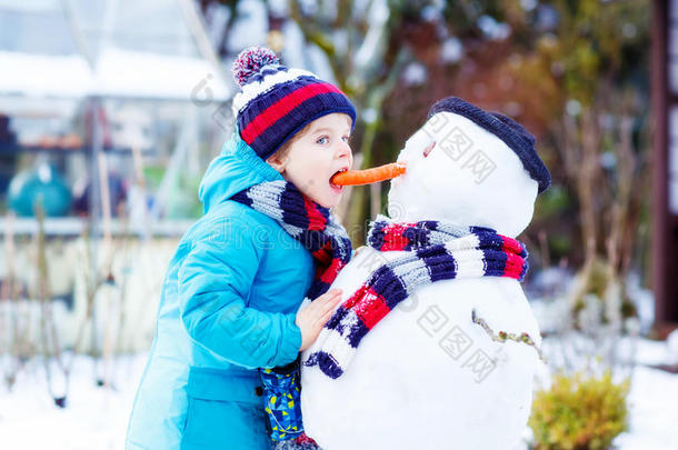 有趣的男孩穿着五颜六色的衣服堆雪人