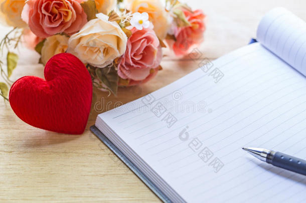 空白笔记本和心与花在木桌上，情人节