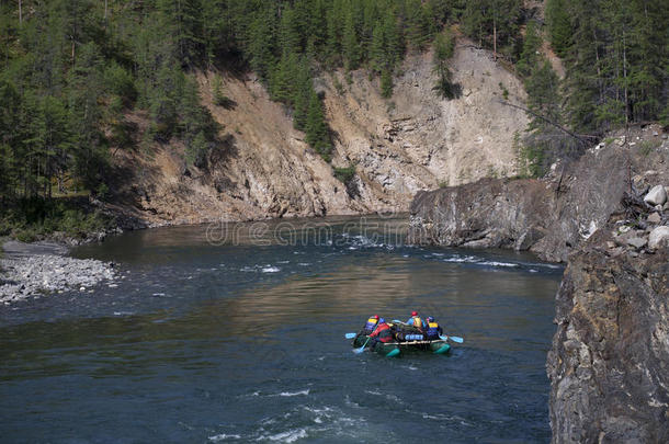 一群游客乘坐筏子沿着河漂流。