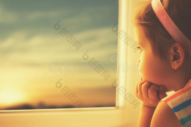 孩子悲伤的小女孩望着窗外的夕阳