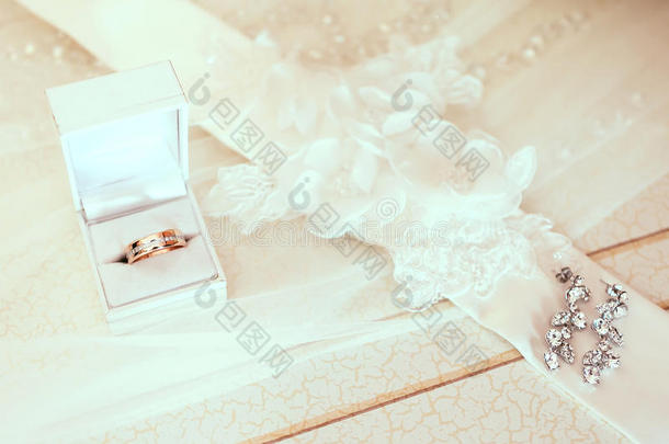 订婚戒指在白色婚礼框与新娘耳环在面纱背景