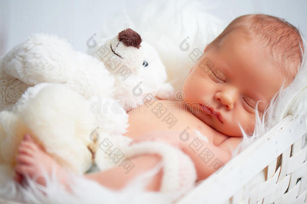 可爱的新生婴儿和玩具泰迪熊睡觉