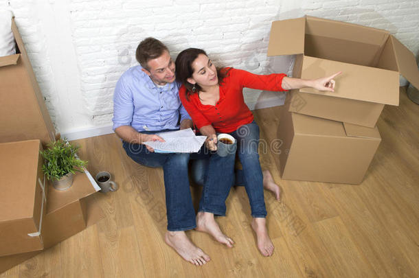 一对夫妇坐在地板上，用电脑笔记本电脑在新房子或公寓里移动