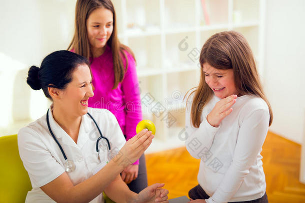 女医生营养师和病人青少年。医生拿着苹果