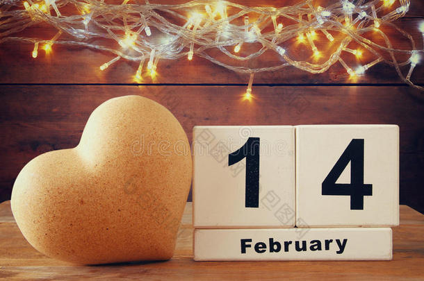 2月14日木制老式日历旁边的心木桌子。 陈年过滤