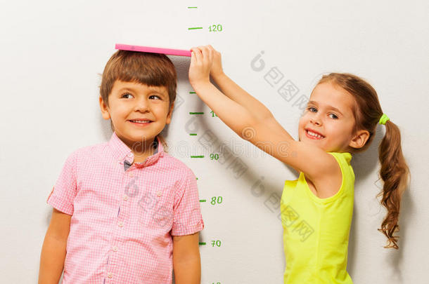 男孩和女孩在家用墙尺<strong>测量身高</strong>