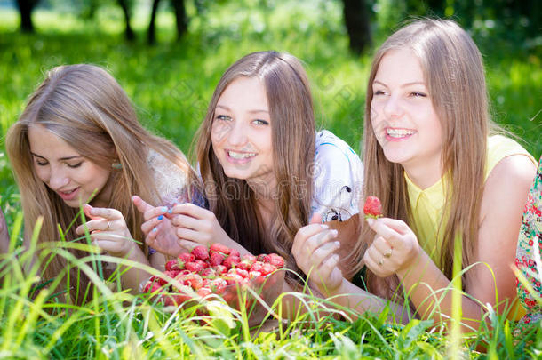 女孩们在明媚的夏日采摘草莓