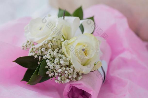 一张彩色的宏观照片，两个伴娘的花手镯，在两朵白色玫瑰的中心有一颗假钻石