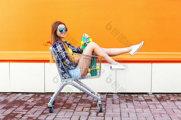 时尚微笑的酷女孩坐在购物车里玩得很开心