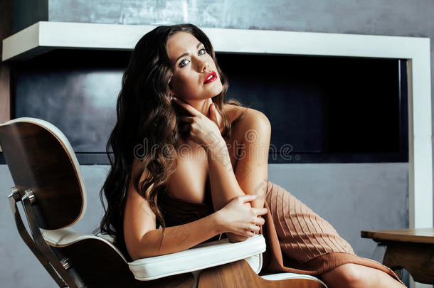 美丽的年轻黑发女人坐在家里的壁炉附近，冬天温暖的夜晚在室内，等待庆祝