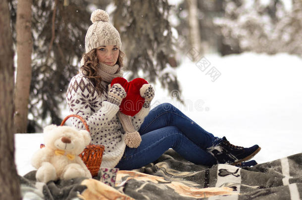 漂亮，漂亮，可爱，漂亮的女孩拿着玩具，手拿大红心的女孩，坐在温暖的格子里，在冬林里野餐