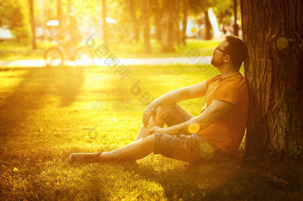 一个快乐、体贴的梦想家，坐在公园的绿草地上