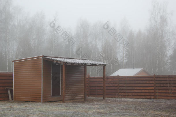 谷仓在薄雾中的冰冻草坪上有棚子