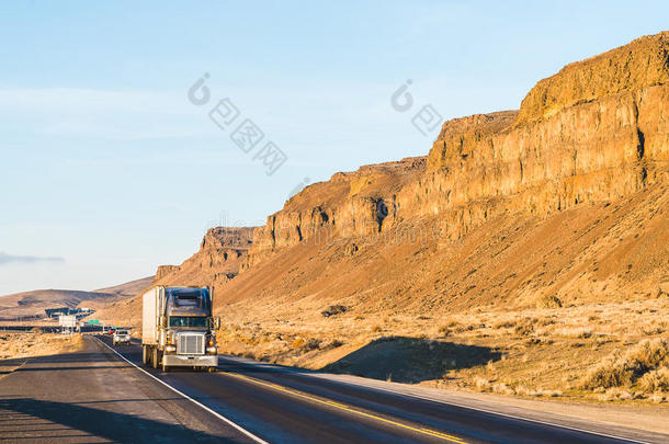 一辆大卡车在日落时行驶，背景是山。