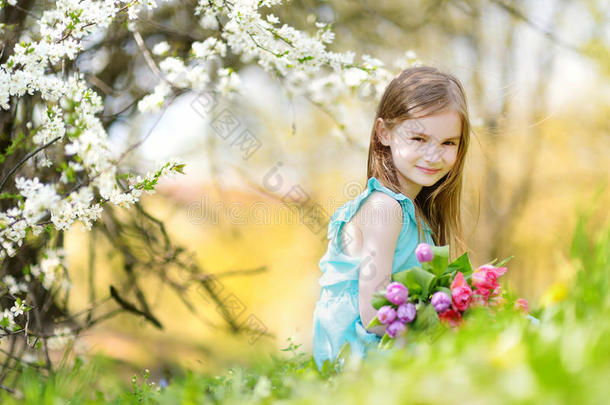 可爱的小女孩拿着郁金香给她的母亲在樱桃园