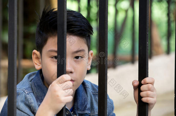 亚洲男孩把手伸进监狱，<strong>看着窗外</strong>
