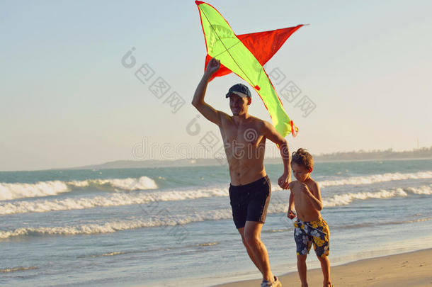 父亲带着儿子，日落在海边带着风筝，幸福的家庭