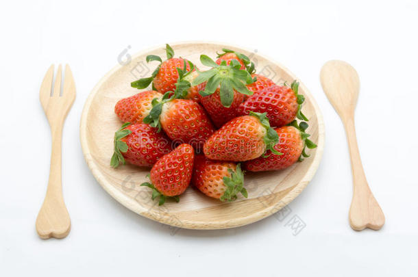 用勺子和叉子在木碟里放新鲜草莓