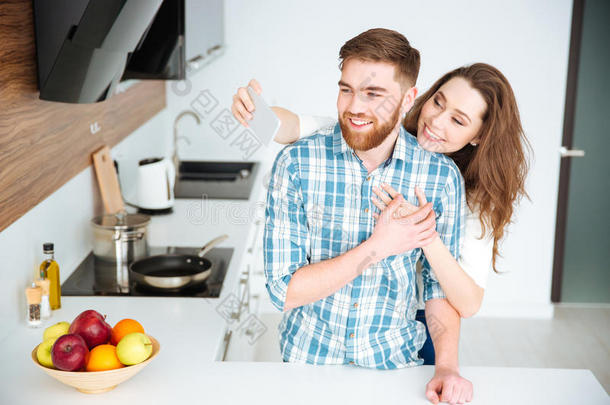 一对夫妇在厨房的智能手机上拍自拍照片