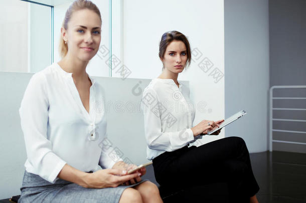 优雅的两个女团队在等待开始面试的时候拿着数字平板电脑和手机，