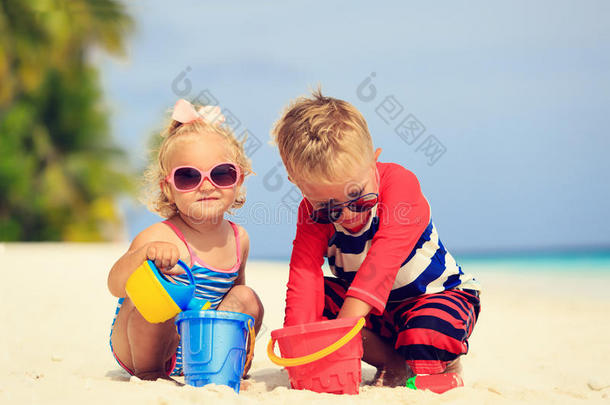 可爱的小男孩和蹒跚学步的女孩在海滩上玩沙子