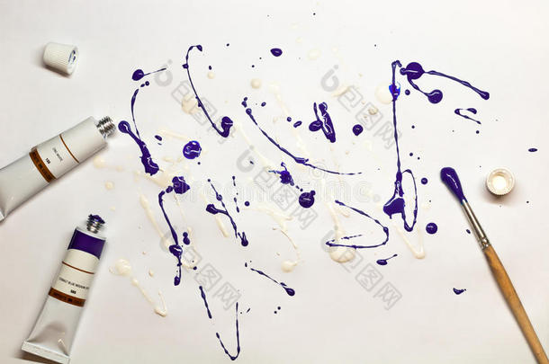 艺术表达。 一张纸上的紫色和白色<strong>油漆</strong>的印迹，旁边有一把刷子和油色管。