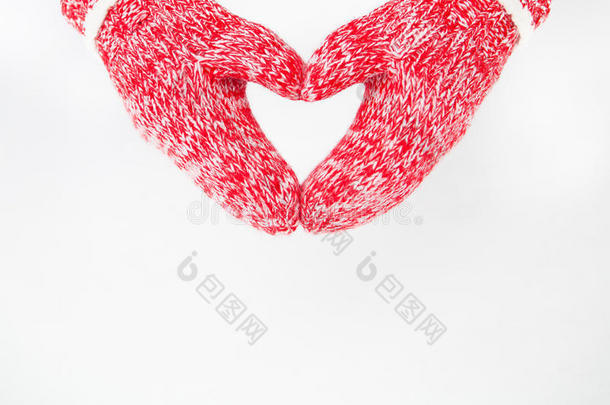 双手戴着红色手套，在冬天的自然背景下以心脏的形式出现