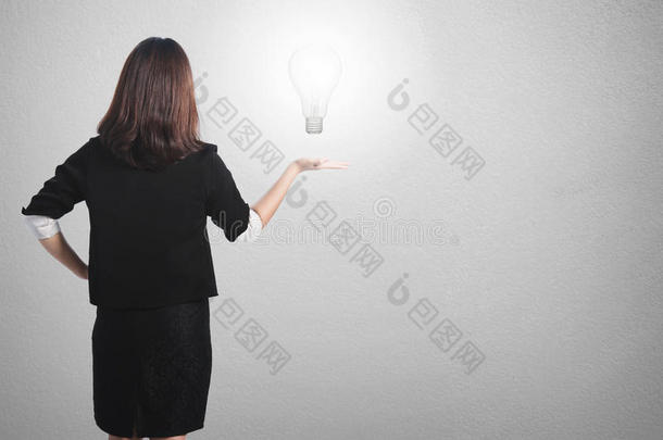 商业妇女为她的计划持有想法灯泡墙