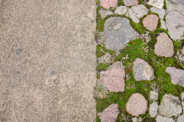 砖铺装块。 鹅卵石路面。 古老的石径上的绿色苔藓。 道路路面，草绿色。 苔藓试图在两者之间生长