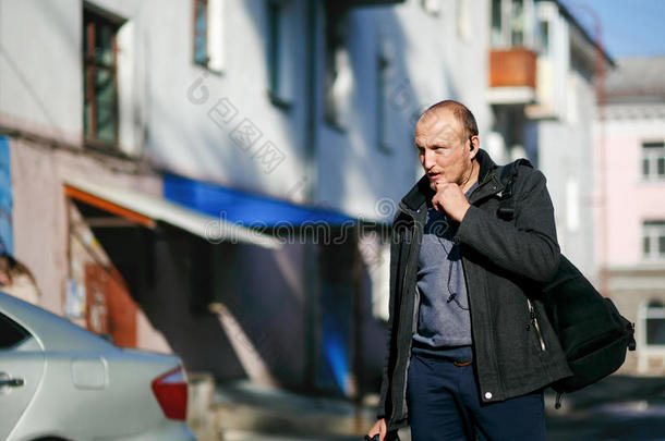 残忍的街头摄影师手拿相机漫步在城市的街道上，用对讲机免费交谈。