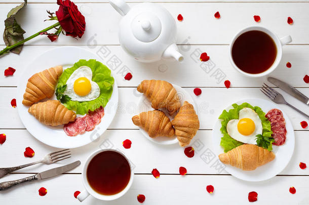 情人节为夫妇提供早餐，包括<strong>心形</strong>煎蛋、沙拉、牛角面包、香肠、玫瑰<strong>花瓣</strong>