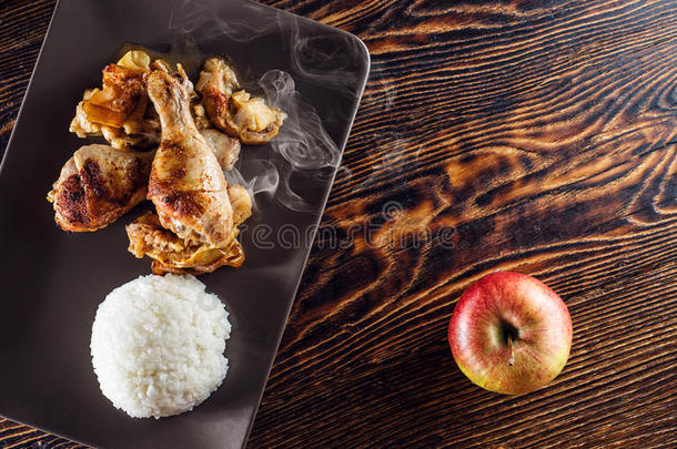 苹果上的鸡肉大腿和白米饭，木桌上的食物，餐厅的产品摄影