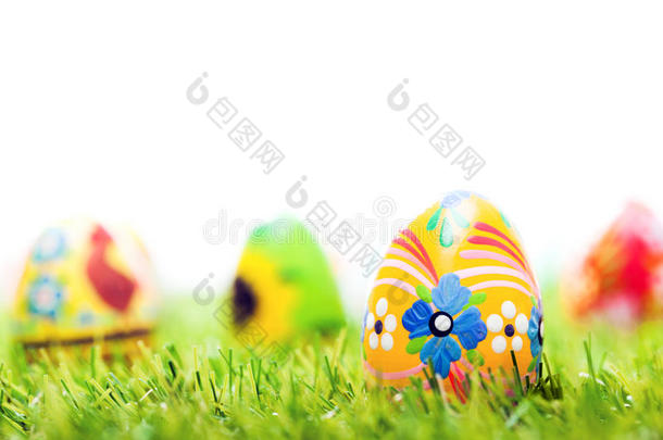 五颜六色的手绘复活节彩蛋在草地上。 春季主题，白色复制空间