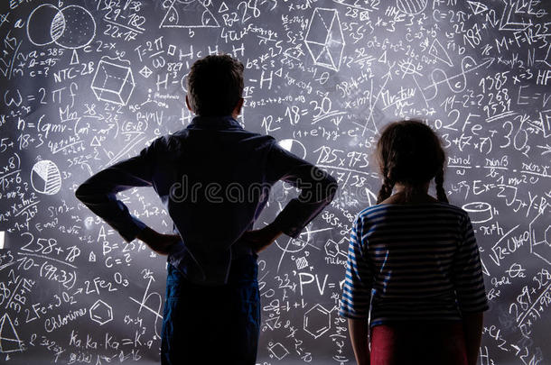 可爱的小男孩和女孩在一个大黑板前。