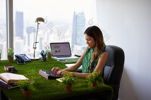 环保主义者的女人在办公桌上用平板电脑键入电子邮件