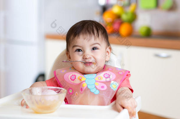 有趣的婴儿在厨房里<strong>用勺子</strong>吃自己