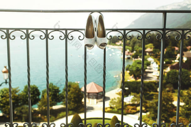 优雅的豪华婚礼鞋挂在酒店阳台、大海和拖车上
