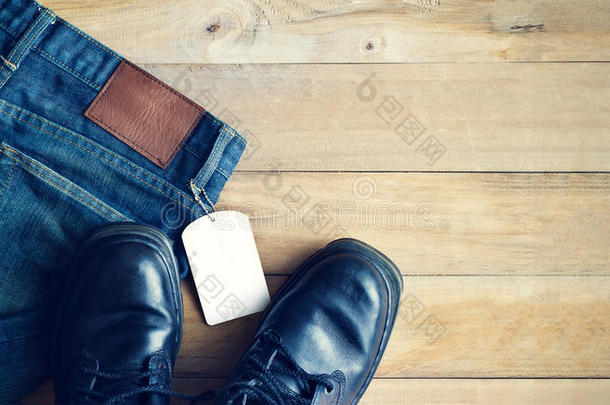 蓝色牛仔裤，白色空白标签和鞋子在木制背景上