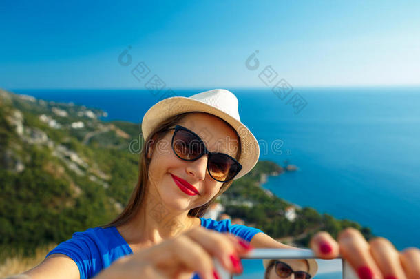 女孩<strong>戴</strong>着帽子，在海边，亚得里亚海的背景上用智能<strong>手机自拍</strong>