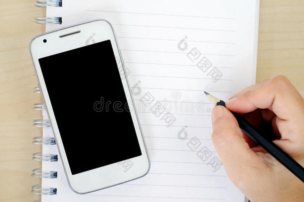 手拿铅笔在纸条和智能手机背景上